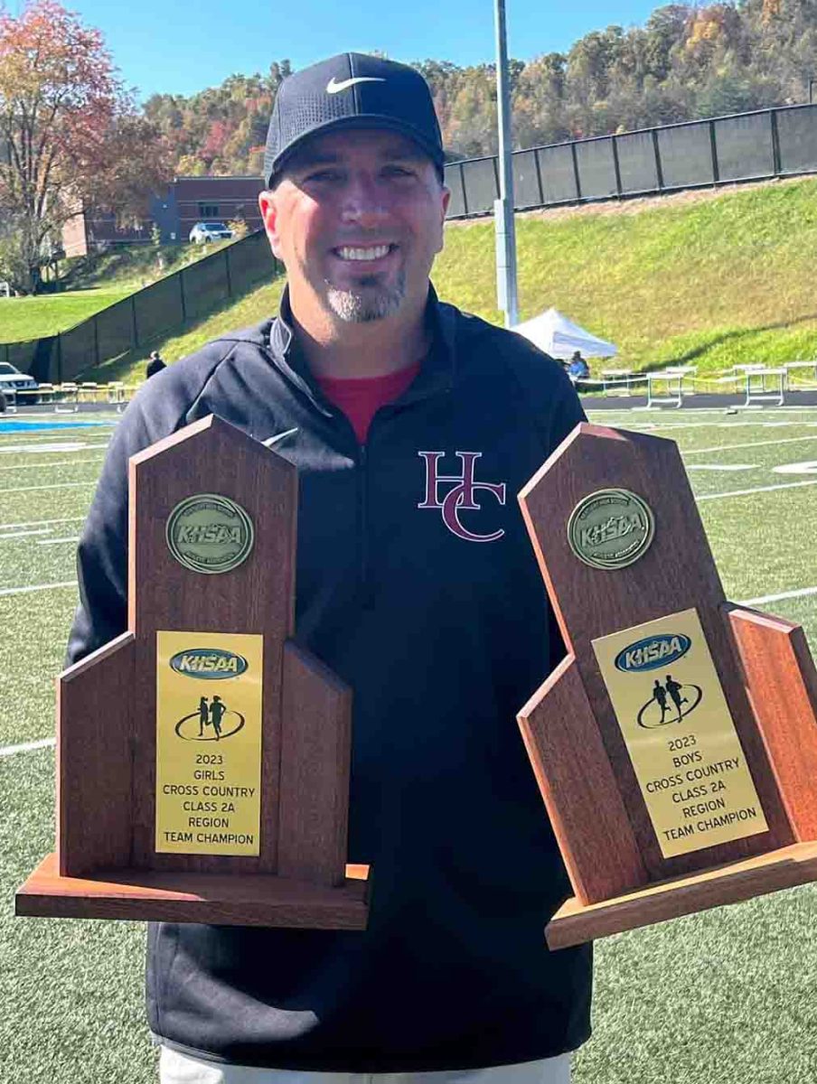 Harlan County cross country coach Ryan Vitatoe is pictured with the Region 7 trophies for both the girls and boys teams after HCHS won both regional titles on Saturday at Morgan County High School.