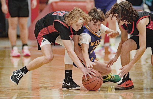 Brenton Bargo (left) and Kaden Jones, both of James A. Cawood, battled with Wallins Mason Howard for a loose ball in middle school basketball action Monday.