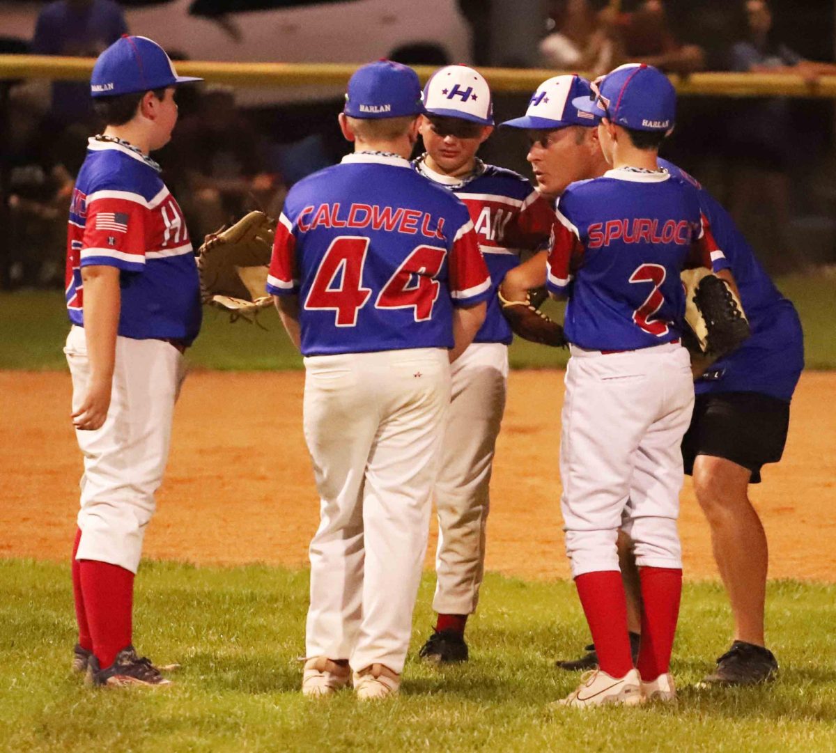 Harlan All Stars coach Anthony Nolan talked with his infielders during a break in District 4 Tournament action Monday. Harlan rallied with seven runs in the sixth inning to pull even before falling 8-7 to Williamsburg.