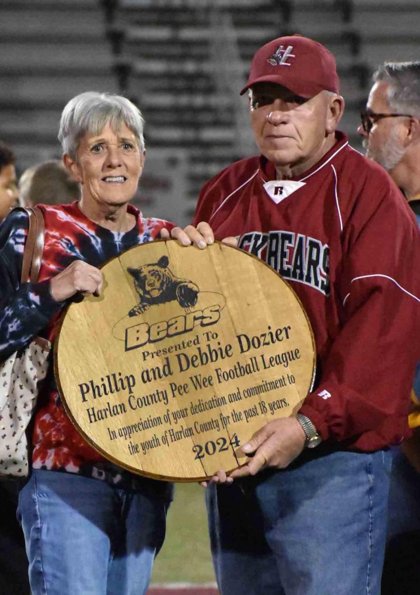 Harlan County Pee Wee League coaches honored Phillip and Debbie Dozier for their service to the league over the past 18 years. The Doziers were surprised with a presentation during Youth Night at the Harlan County-South Laurel game on Friday. They were presented an award denoting their service to the girls and boys of Harlan County Schools in the cheer, flag football, pee wee football and junior leagues. The Doziers have donated their time each year to oversee the operations of the league, impacting hundreds of children  over the years. As an added treat, Debbie Dozier was asked to lead the players in a dance to “YMCA,” proving to be a crowd favorite.