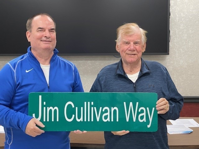 Former Cawood player and coach Rick Parsons (left) and Harlan County board member Wallace Napier held one of the signs to mark Jim Cullivan Way at James A. Cawood Elementary School.