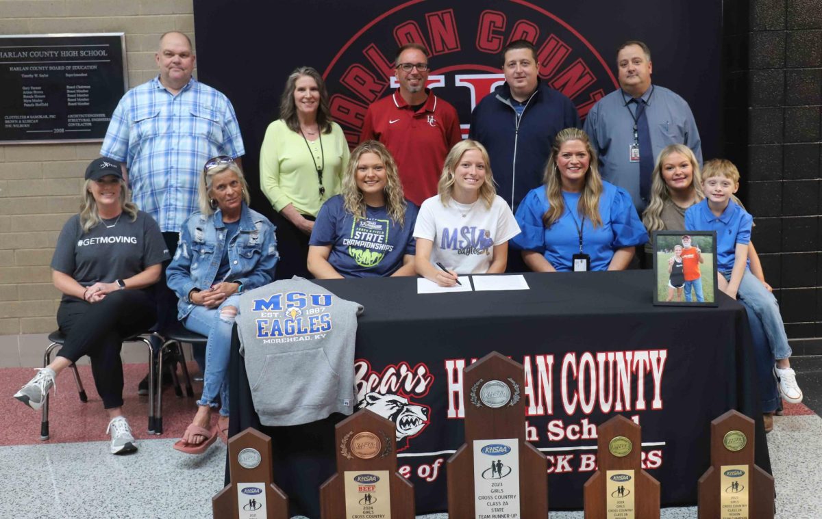 Harlan County senior Peyton Lunsford signed to continue her academic and athletic careers at Morehead State University. Pictured with Lunsford are, from left, front row: Kristie Farley, Karen Givens, Taylor Lunsford, Paige Lunsford, Rylee Napier and Mitchell Lunsford; back row: First Priority leader Bo Lee, HCHS Principal Kathy Napier, HCHS coach Ryan Vitatoe, HCHS athletic director Eugene Farmer and Harlan County School assistant superintendent Brett Johnson.