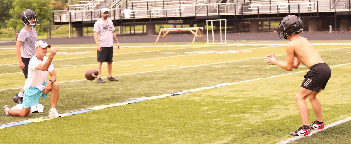 Harlan County coach Jacob Saylor tossed the ball to senior running back Gage Bailey during a drill at a practice session last week.