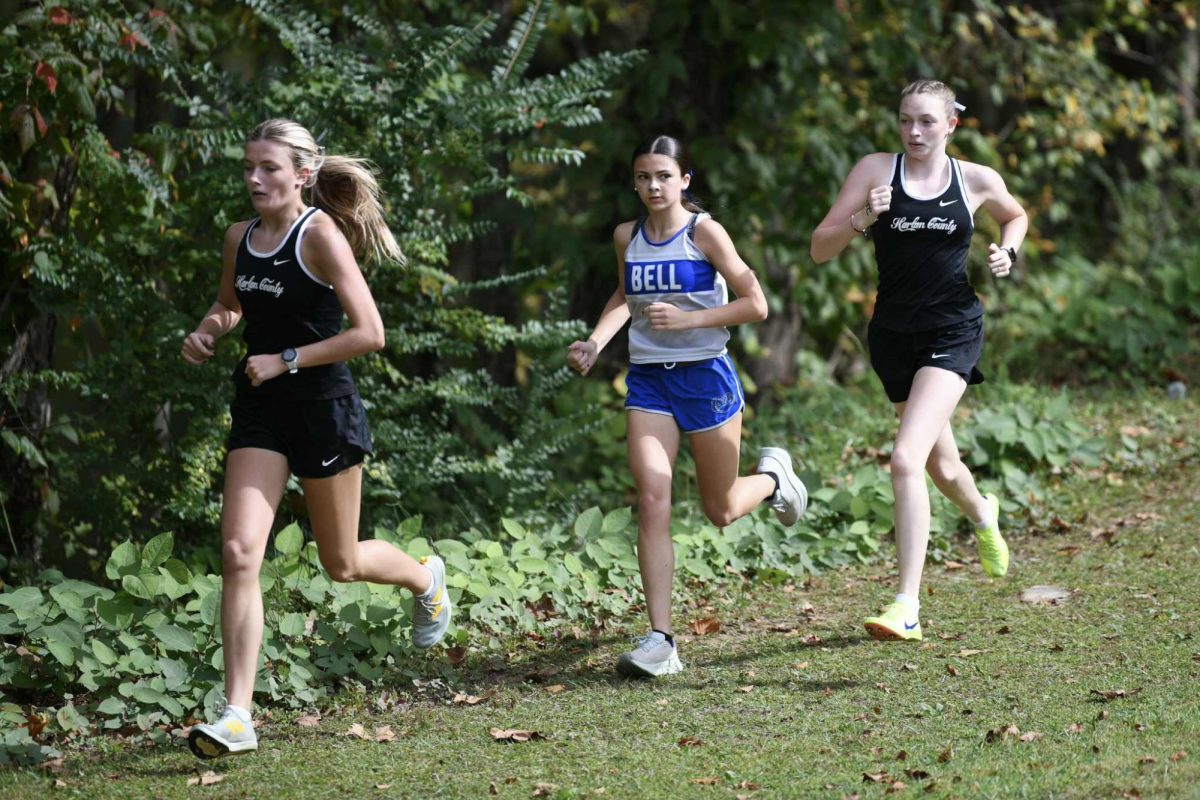 Harlan County's Lauren Lewis (left) and Kiera Roberts each finished in the top five as the Lady Bears won the Bob Howard Invitational and Area 9 races on Saturday at the HCHS course. Bell County's Abagail Johnson is also pictured.