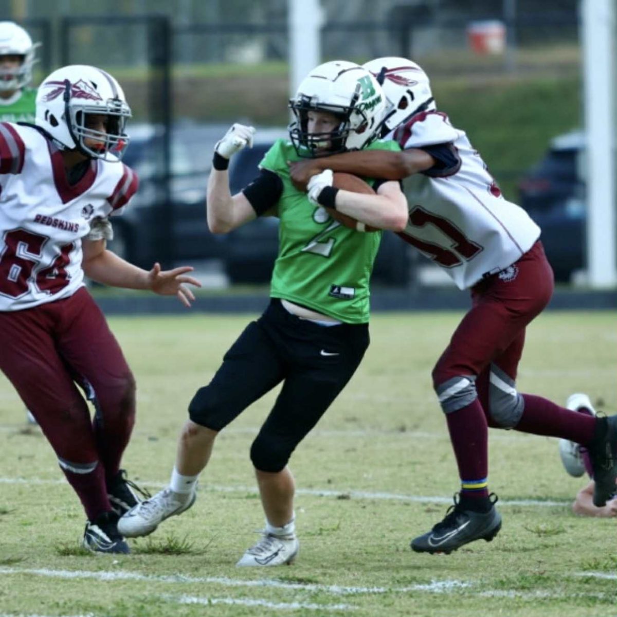 Harlan running back Rush Luttrell battled for yardage against Cumberland defenders Lucas Miles (64) and Ja’Vontae Stewart in fifth- and sixth-grade football action Thursday.