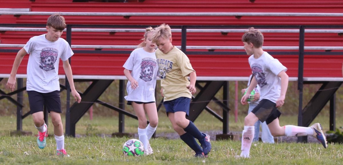 Evarts’ Easton Short dribbled through Cumberland defenders Conner Banks (left) Rose Jones and Jake Cornett in county soccer league action earlier this season.