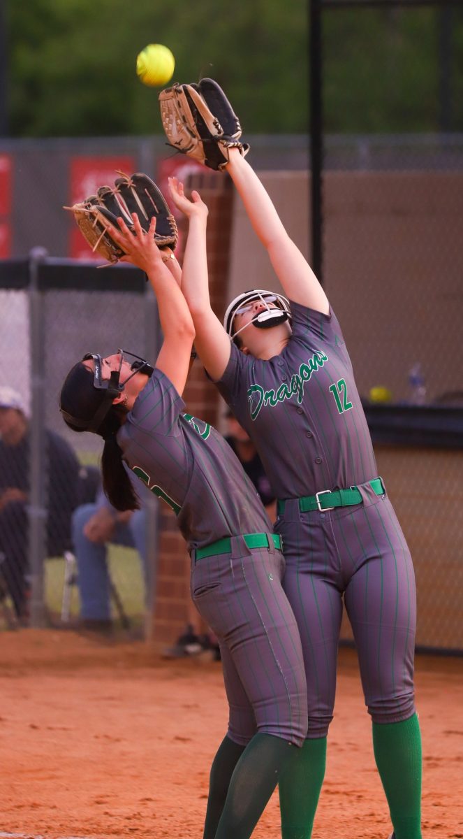 Harlan pitcher Adelynn Lewis (left) and first baseman Shaedyn Crow went after a pop up in Monday's game at Harlan County. Lewis made the catch and also pitched a one-hitter as the Lady Dragons won 8-5.
